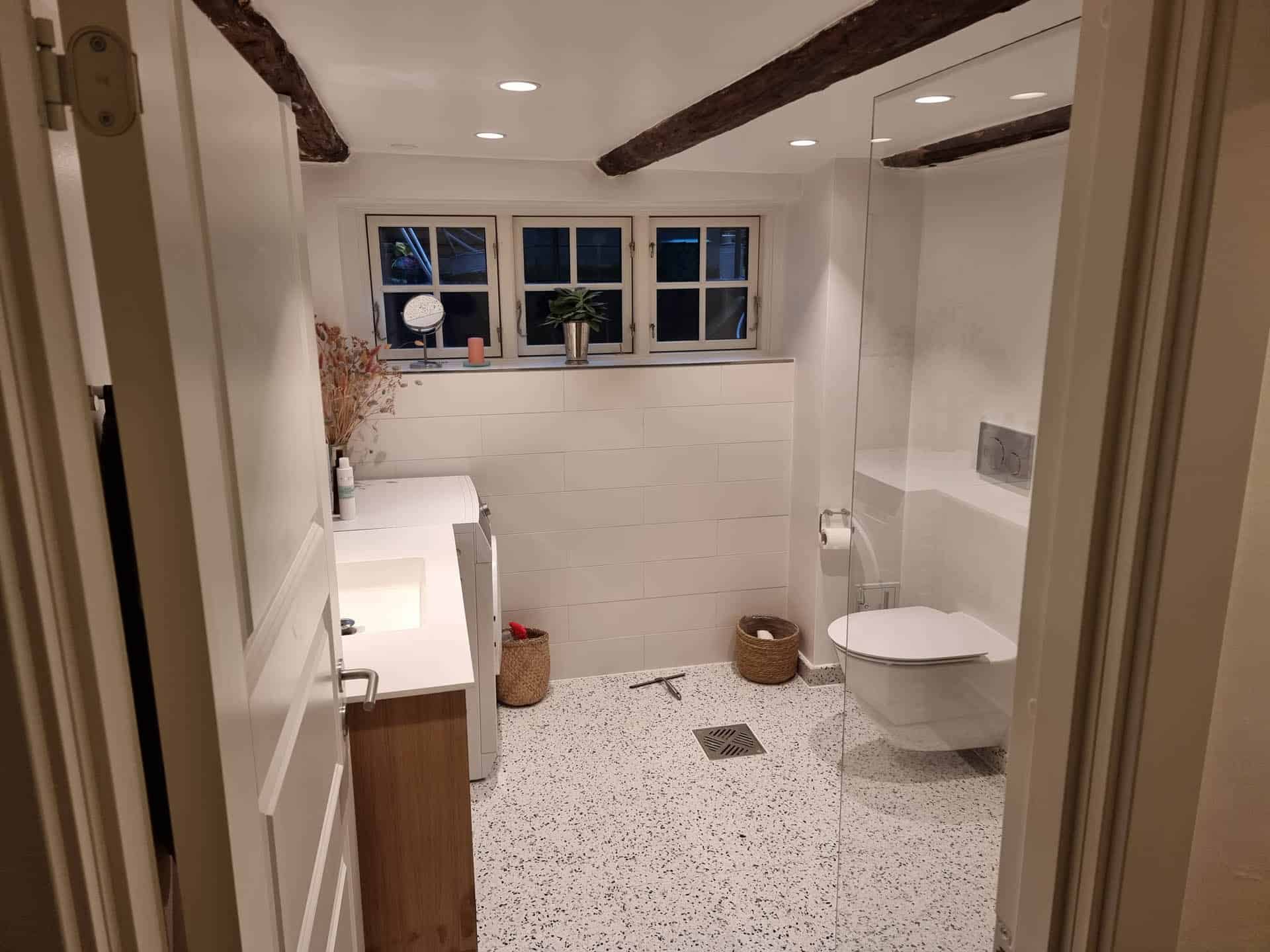 Terrazzogulv og hvide fliser på badeværelse.